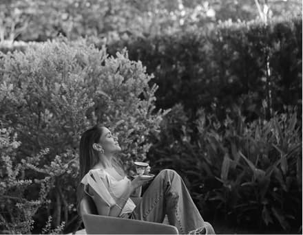 A woman resting in a garden with a cup of tea